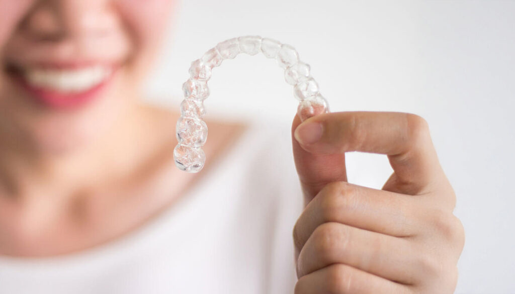 Asian Woman Holding Clear Aligners