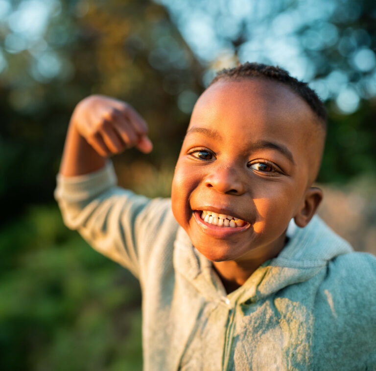 A Little Boy Flexing His Arm Outside