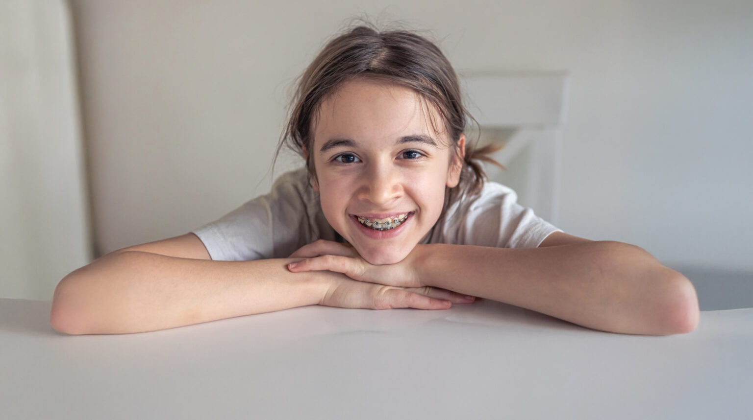 A Teen With Braces Smiling On A White Table