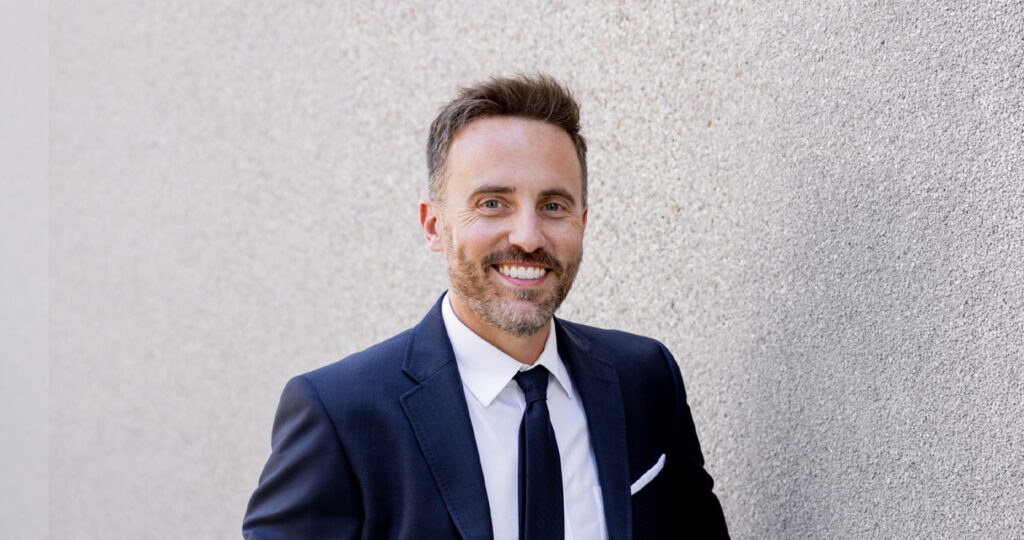 Dr Adam Rudmann In A Suit Against A Rock Wall Jpg