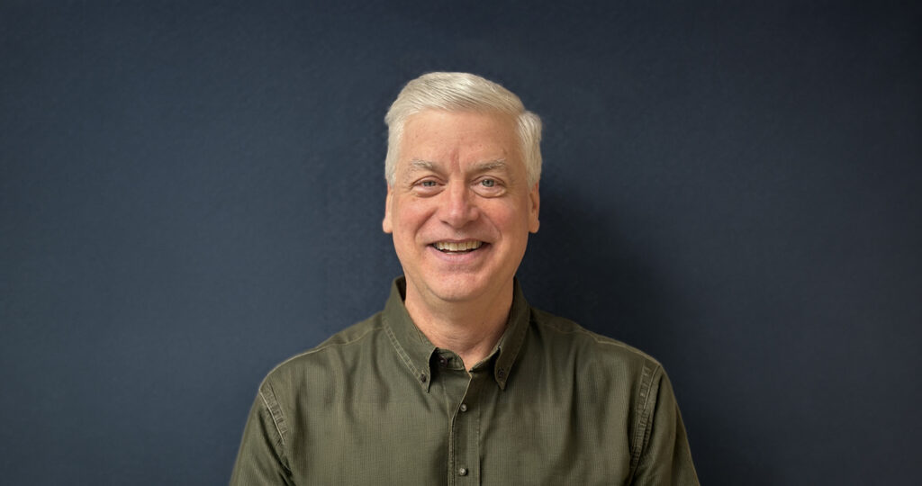 Dr Lang In A Green Shirt In Front Of A Blue Background