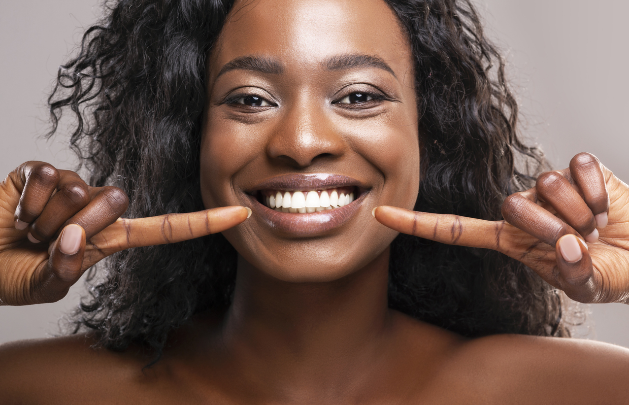 Dark Skinned Woman Pointing At Her Teeth