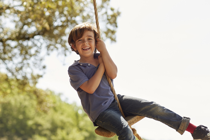 cheerful boy playing on swing.