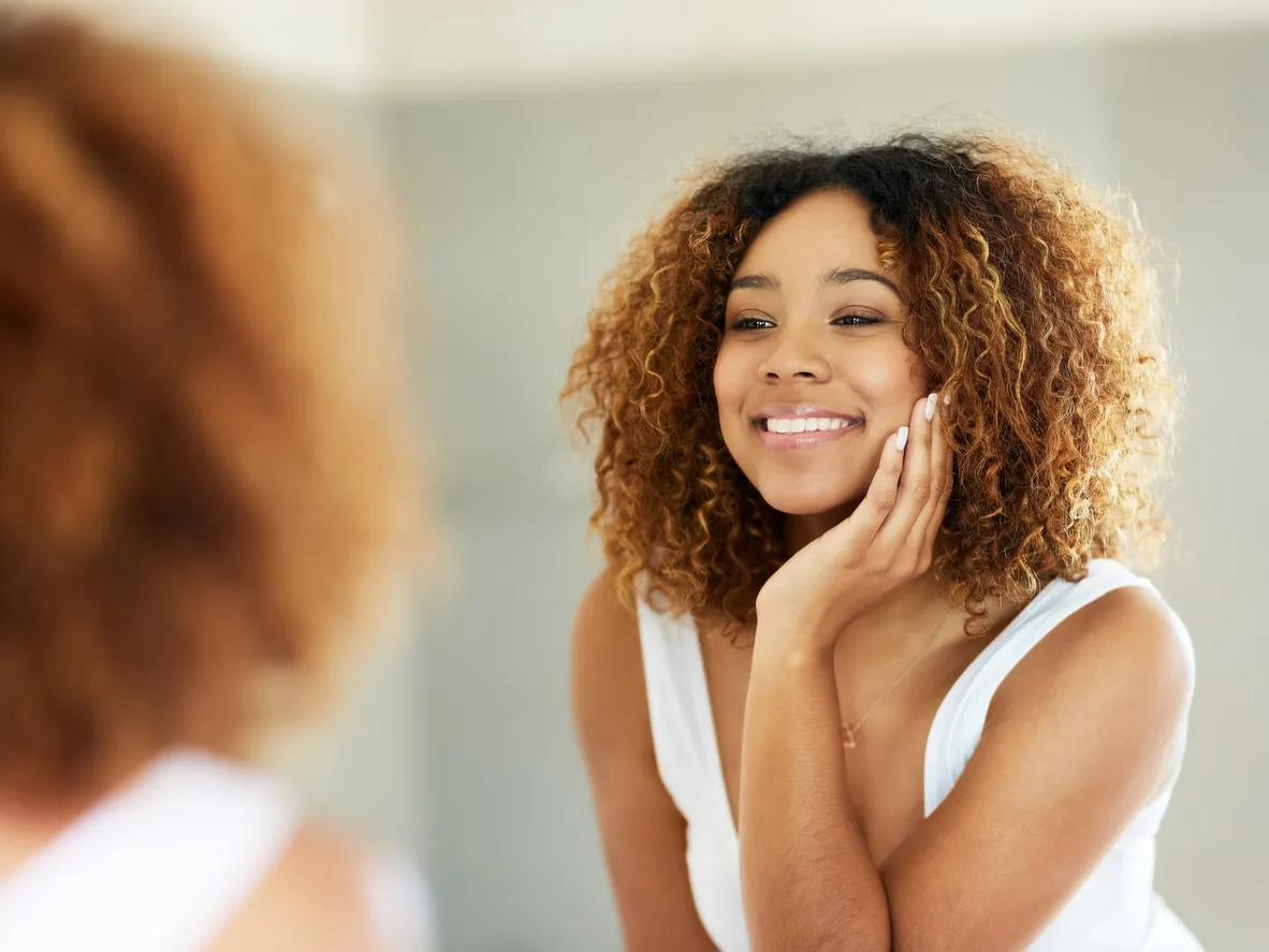 A Beautiful Woman Admiring Her Smile In A Mirror